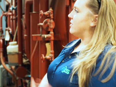 Crystal Camp, business student intern for Fairbanks Energy Services, in a boiler room with HVAC systems