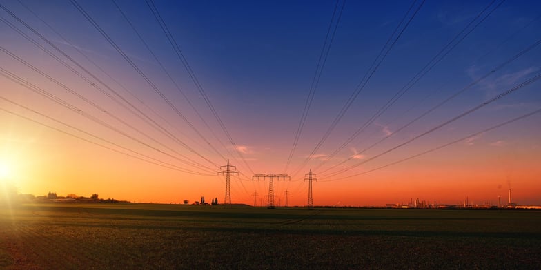 Photo of a sunset, with powerlines and towers cast in black against the sky.