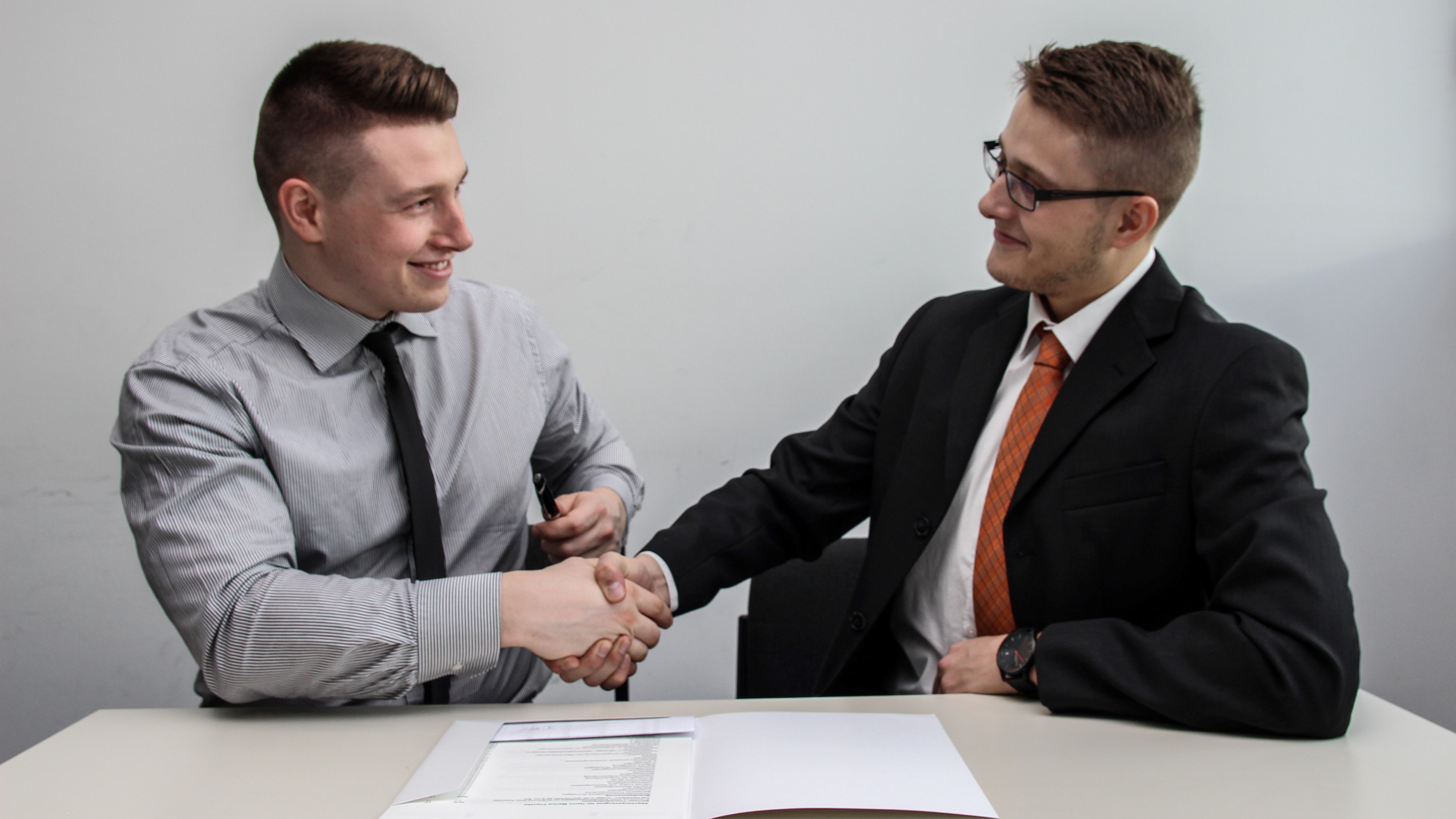 photo of two men at a table shaking hands, representing a deal for energy efficiency investment between a client and an ESCO